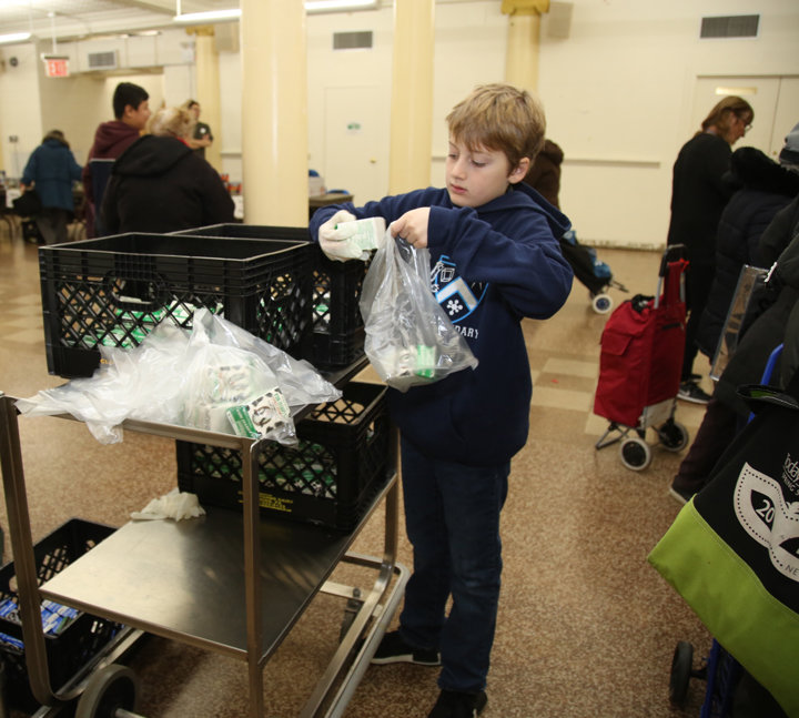 Jack van Schaik, a student in Ascension’s religious education program, bags milk for the pantry.